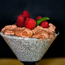 Chia Pudding topped with Raspberry Mousse and garnished with fresh raspberries with a sprig of basil