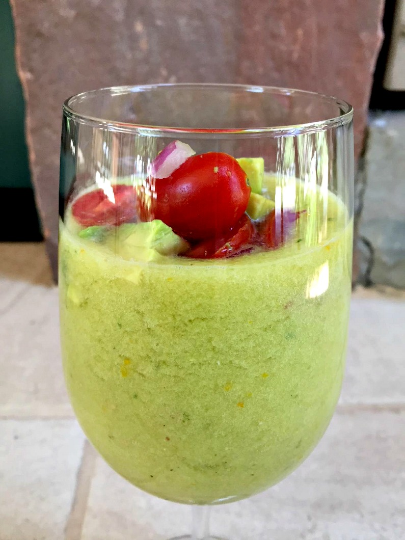 Yellow Gazpacho garnished with avocado, tomatoes, and onions