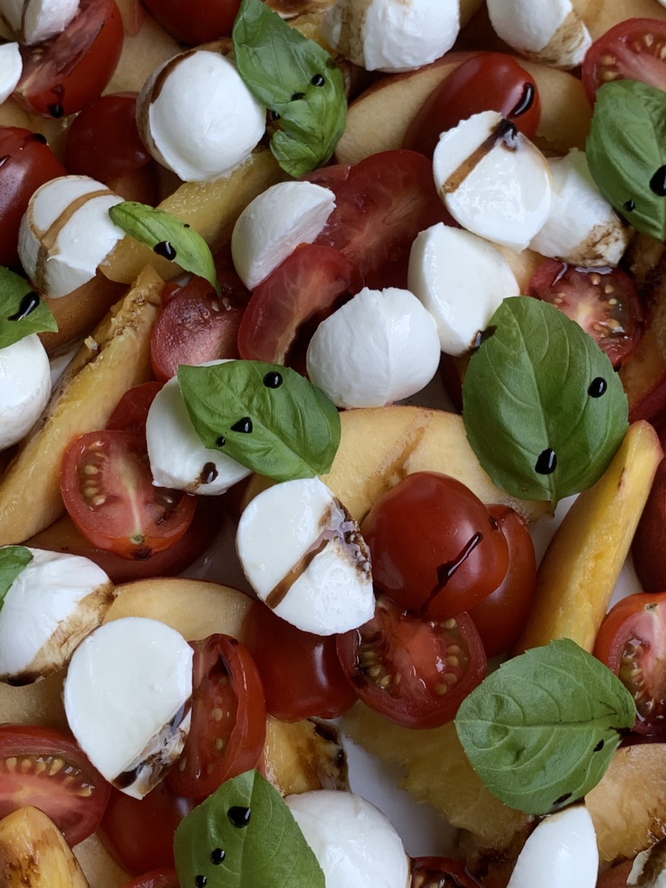 Grilled Peaches with mozzarella balls, tomatoes , basil, and balsamic reduction